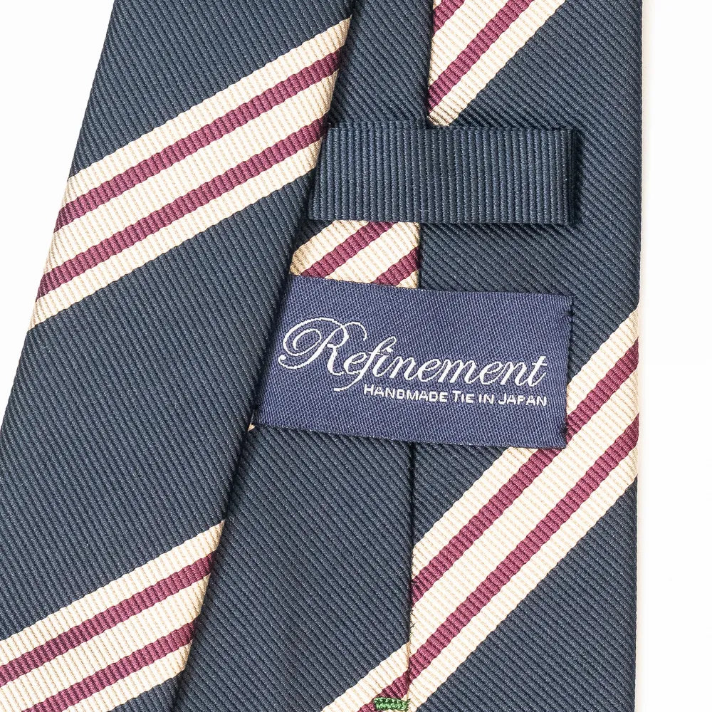 Close-up of the Refinement repp stripe neck tie showing the textured silk weave and brand label detail.