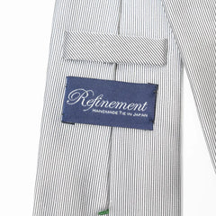 Close-up of the Refinement stripe neck tie showing textured silk weave and brand label detail.
