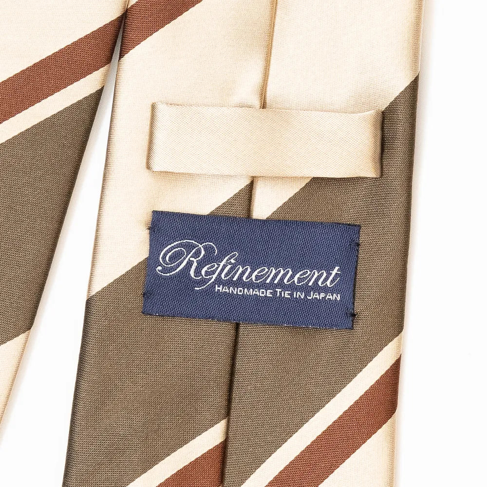 Close-up of the Refinement stripe neck tie showing textured silk weave and brand label detail.
