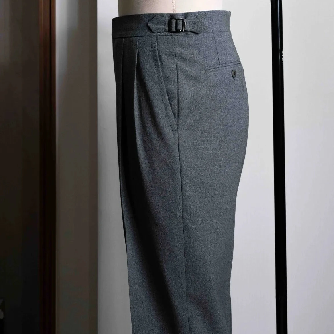 Side view showing the leg profile, side seam, and fluid movement of the sartorial wool fabric.