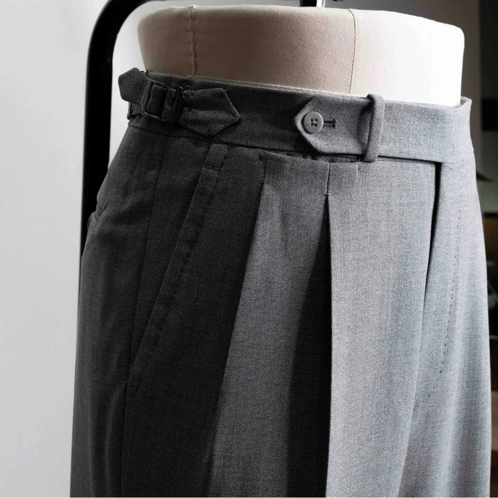 Close-up of the waistband showing button closure, belt loops, stitching precision, and sartorial construction.