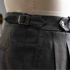 Close-up of the waistband showing button closure, belt loops, stitching precision, and clean sartorial construction.