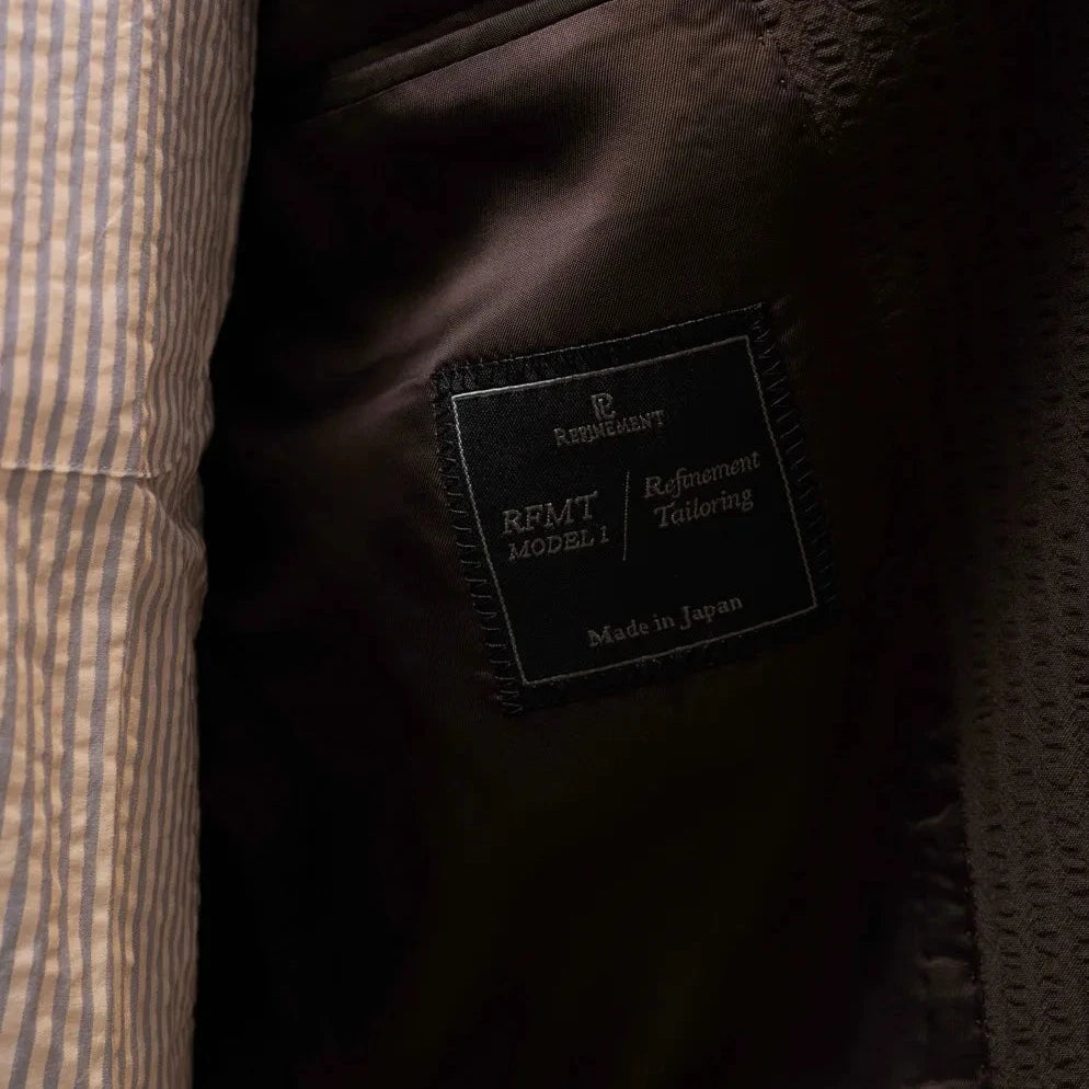 Close-up of the interior trousers label showing Refinement branding and Tallia di Delfino fabric marking.