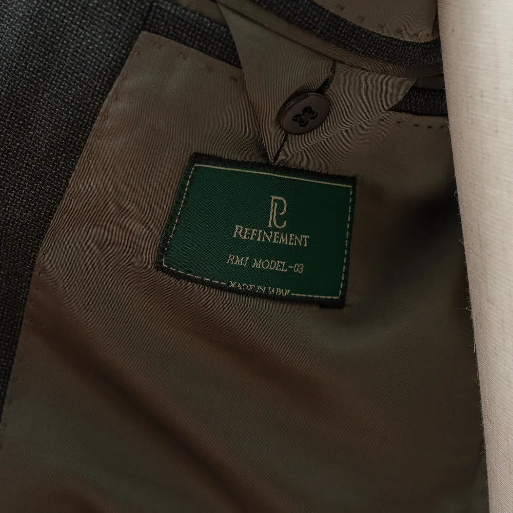 Close-up of the internal label of the RMJ-03 Jacket Green by VBC showing the Refinement × Ring Jacket branding and inner lining construction.