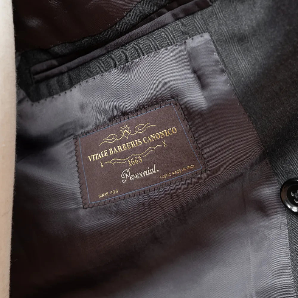 Close-up of the interior labels of the RMJ-04 Suit showing Refinement × Ring Jacket branding and Vitale Barberis Canonico fabric label.