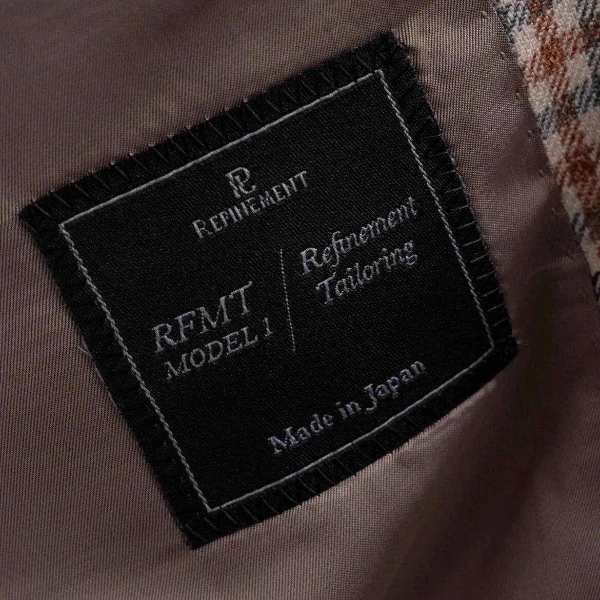 Close-up of the interior label showing Refinement Tailoring branding and E. Thomas cloth identification.