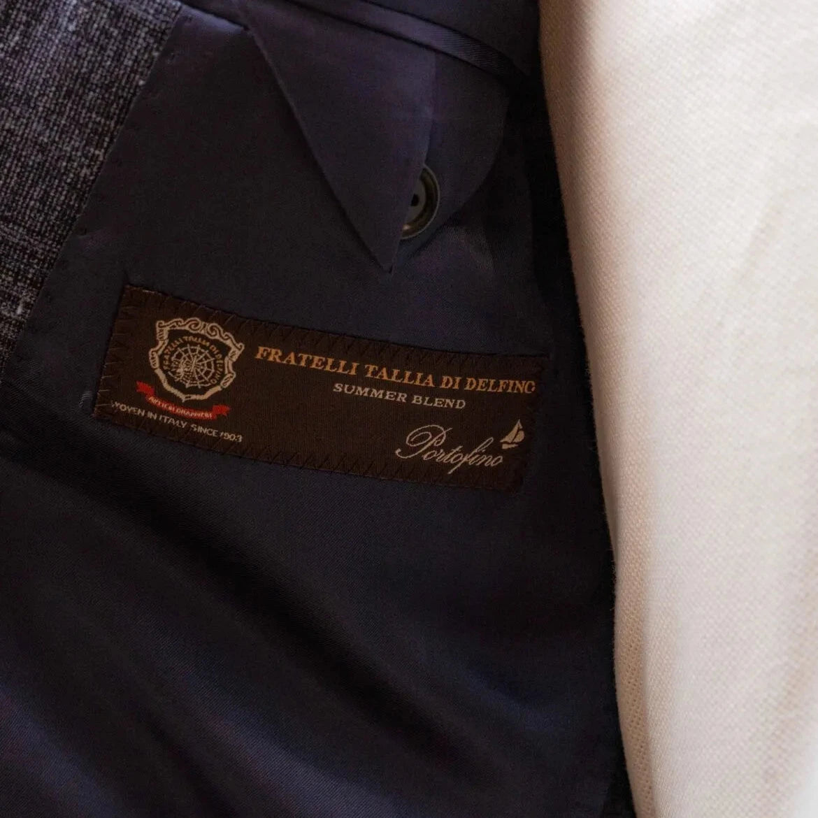 Close-up of the interior label showing Refinement Tailoring branding and Fratelli Tallia di Delfino cloth identification.