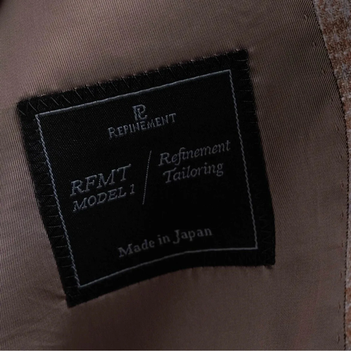 Close-up of the interior label showing Refinement Tailoring branding and Lanificio di Pray fabric marking.