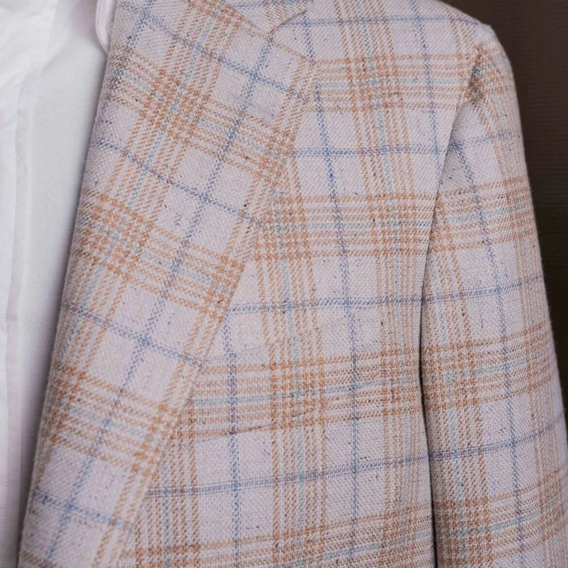 Close-up of the lapel showing notch construction, pick stitching, and the intricate grey glen check weave from Lanificio di Pray.