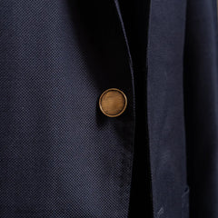Close-up of the front button highlighting fabric texture and finishing.