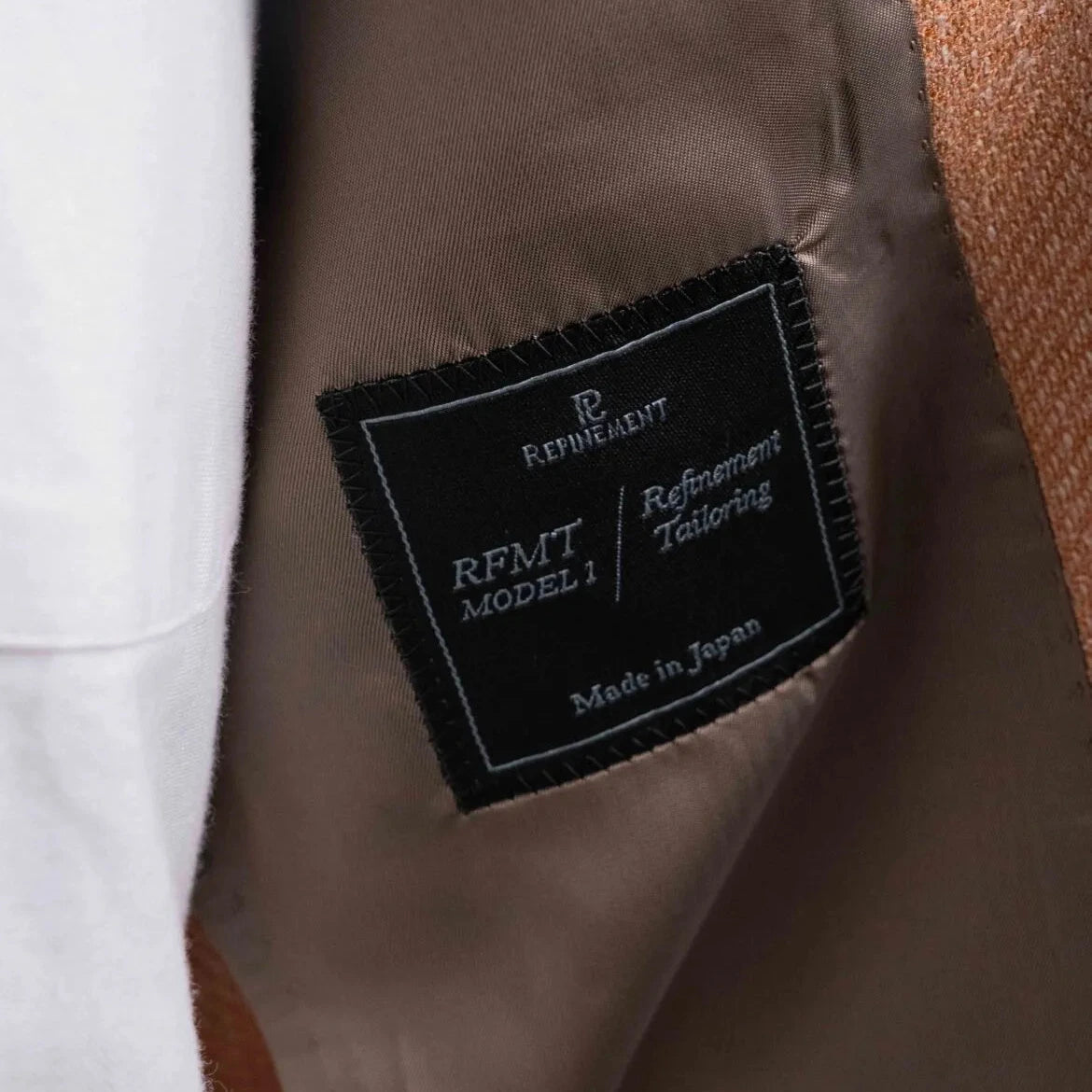 Close-up of the interior label showing Refinement Tailoring branding and E. Thomas cloth identification.