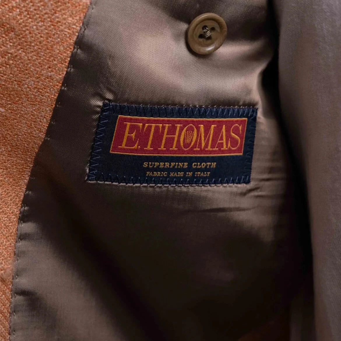 Close-up of the interior label showing Refinement Tailoring branding and E. Thomas cloth identification.