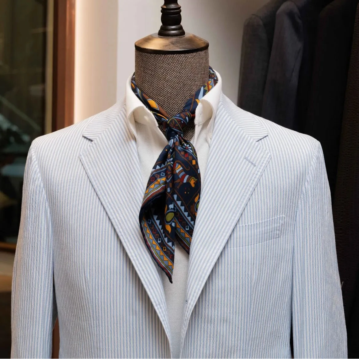 Close-up of the lapel showing notch construction, subtle pick stitching, and the puckered seersucker stripe texture from Biellesi.