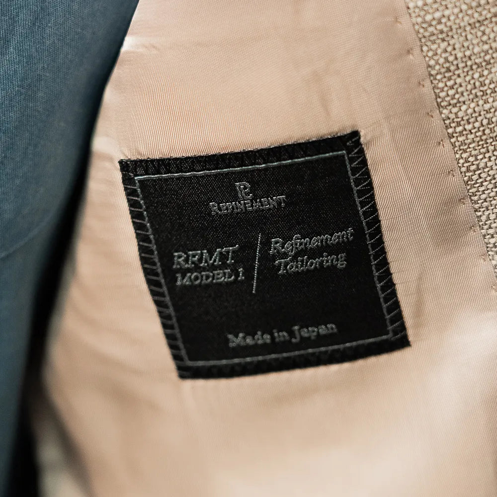 Close-up of the Refinement Tailoring interior brand label showing make, finishing, and clean lining work.
