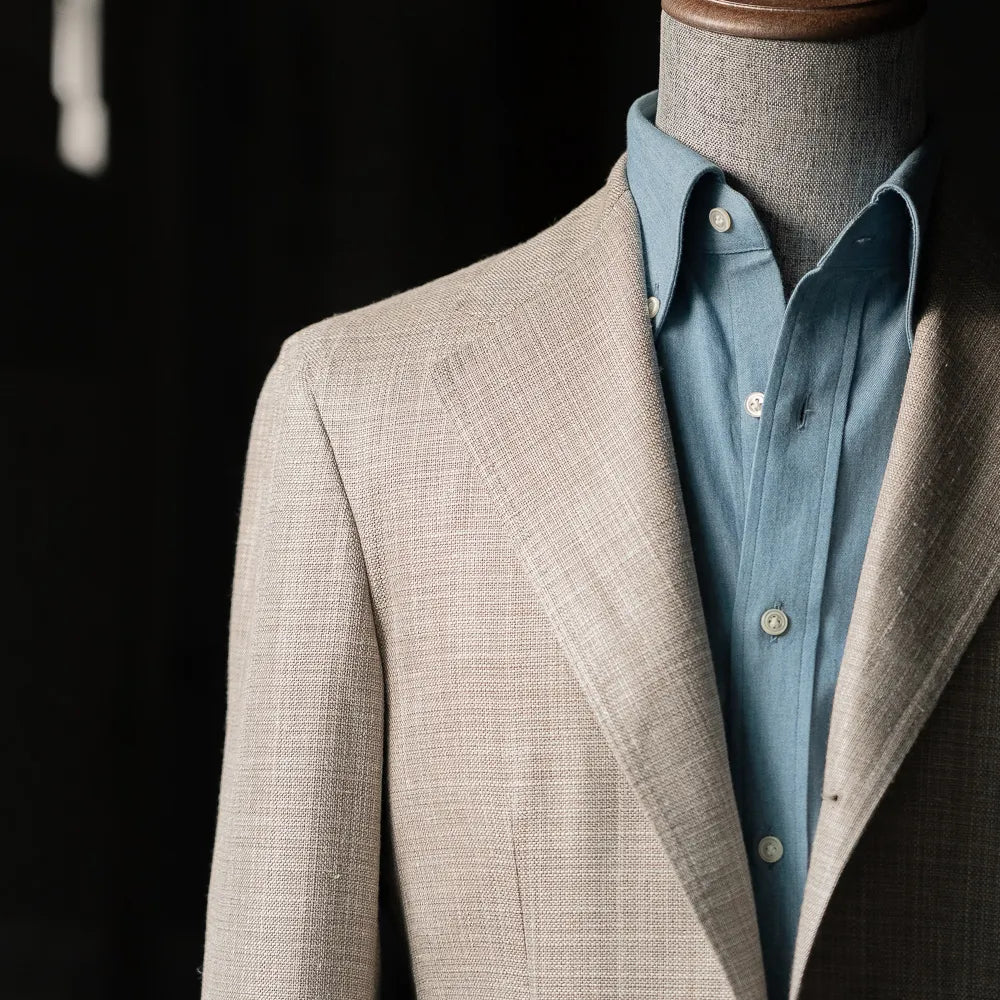 Upper body close-up of the Summertime Beige jacket showing lapel roll, chest pocket, and Loro Piana fabric texture.