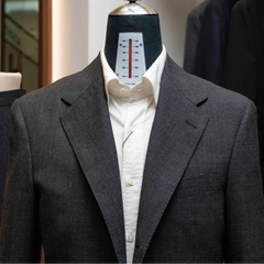 Close-up of the notch lapel showing pick stitching and the refined grey glen check weave from Woodhead.