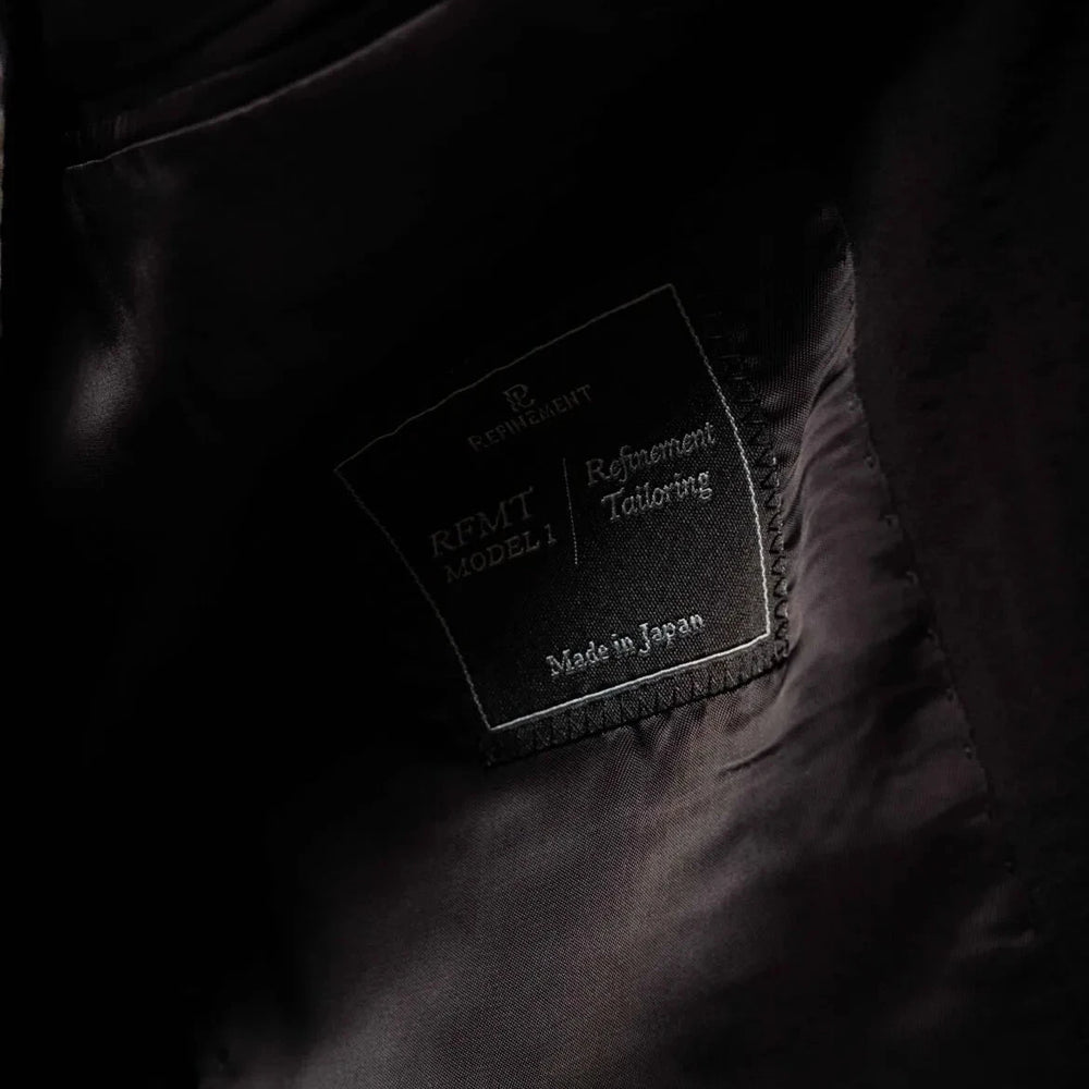 Close-up of the interior label showing Refinement Tailoring branding and Tallia di Delfino cloth identification.