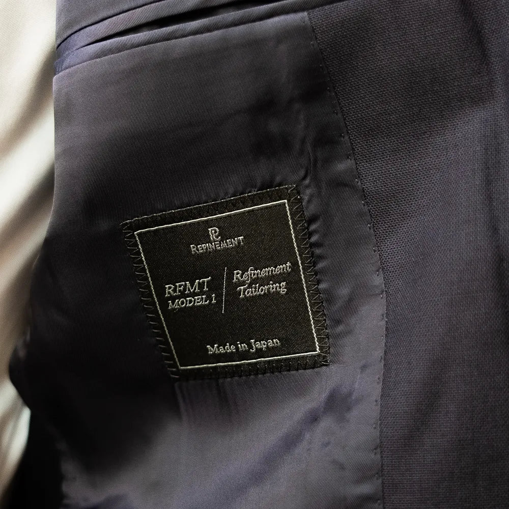 Interior close-up of the Refinement Tailoring brand label showing construction and finishing details.