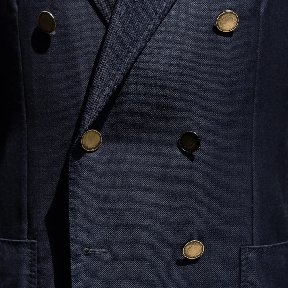 Close-up of the double-breasted button configuration showing fabric texture and refined finishing.
