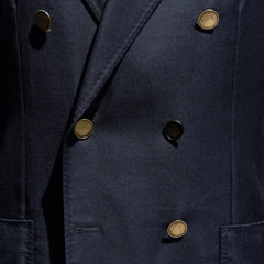 Close-up of the double-breasted button configuration showing fabric texture and refined finishing.
