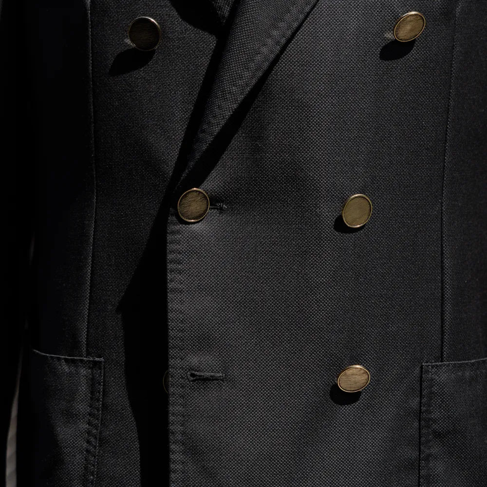 Close-up of the double breasted button configuration showing fabric texture and brass buttons.
