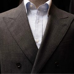 Close-up of the peak lapels showing crisp shape, pick stitching, and the Woodhead mid-grey wool weave.