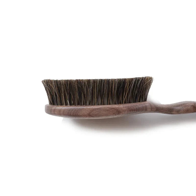 Angled view of the Shoji Horsehair Clothes Brush highlighting the curved handle and bristle density.