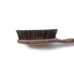 Angled view of the Shoji Horsehair Clothes Brush highlighting the curved handle and bristle density.