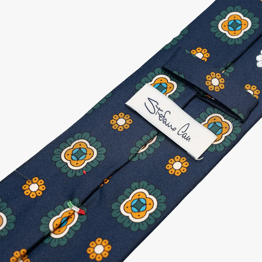 Close-up of the back side of the Stefano Cau floral tie showing the brand label, hand-finished stitching, and clean construction.