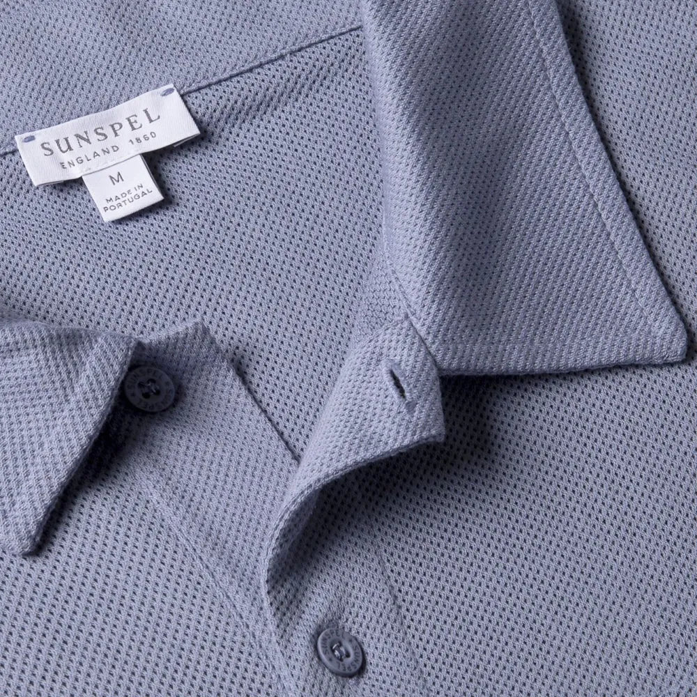 Close-up fabric texture of the Sunspel Riviera Polo Shirt Vintage Blue showing the airy mesh cotton weave.
