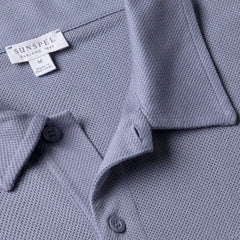 Close-up fabric texture of the Sunspel Riviera Polo Shirt Vintage Blue showing the airy mesh cotton weave.
