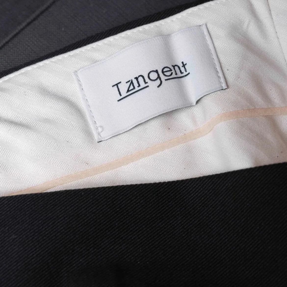 Close-up of the inner label of the Tangent TAN25 Pat Black trousers showcasing branding and craftsmanship.