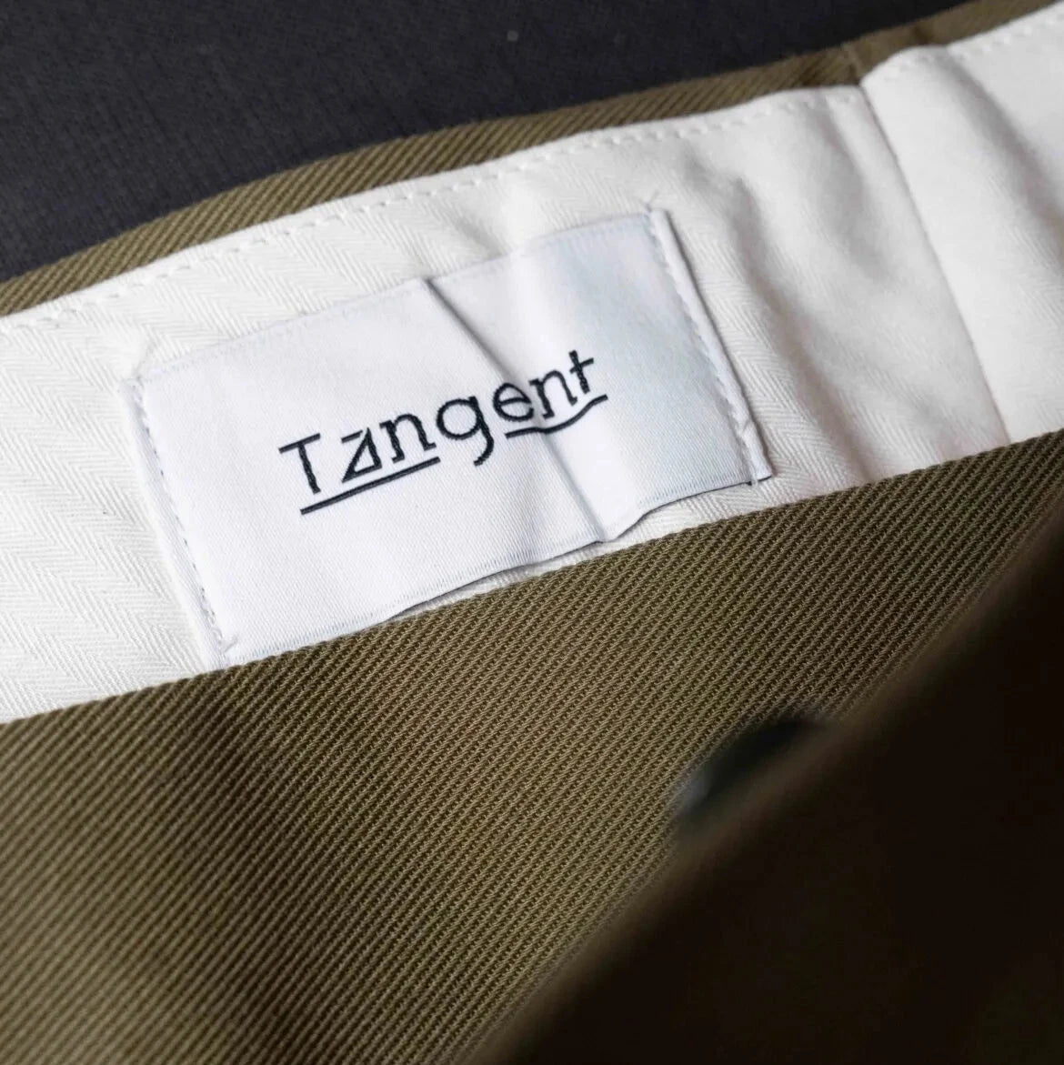 Close-up of the inner label of the Tangent TAN25 Pat Olive trousers showcasing branding and craftsmanship.