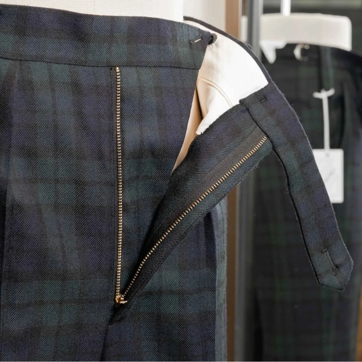 Close-up of the waistband of the Tangent Tan 25° Wool Check Black Watch trousers showing adjusters and button details.