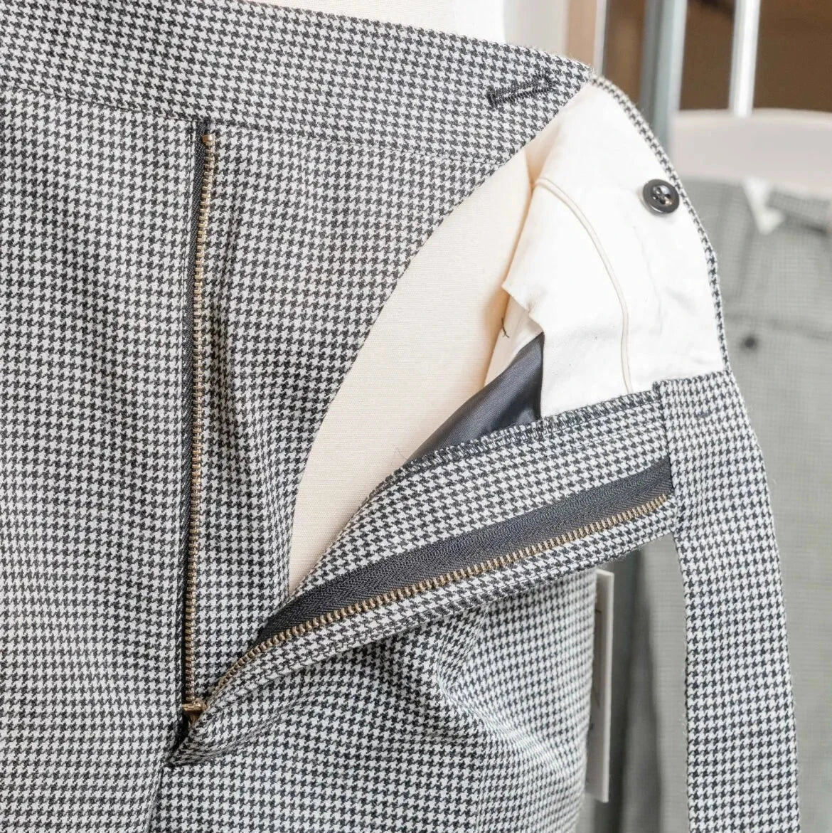 Close-up of the waistband of the Tangent Tan 25° Wool Check Hound Tooth trousers showing adjusters and button details.
