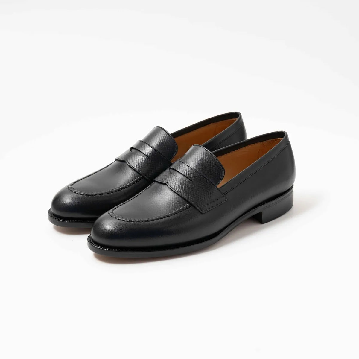 A pair of TLB Mallorca 315 Jones Penny Loafers in black hatch grain leather, shown at an angle to highlight the grain texture and classic silhouette.