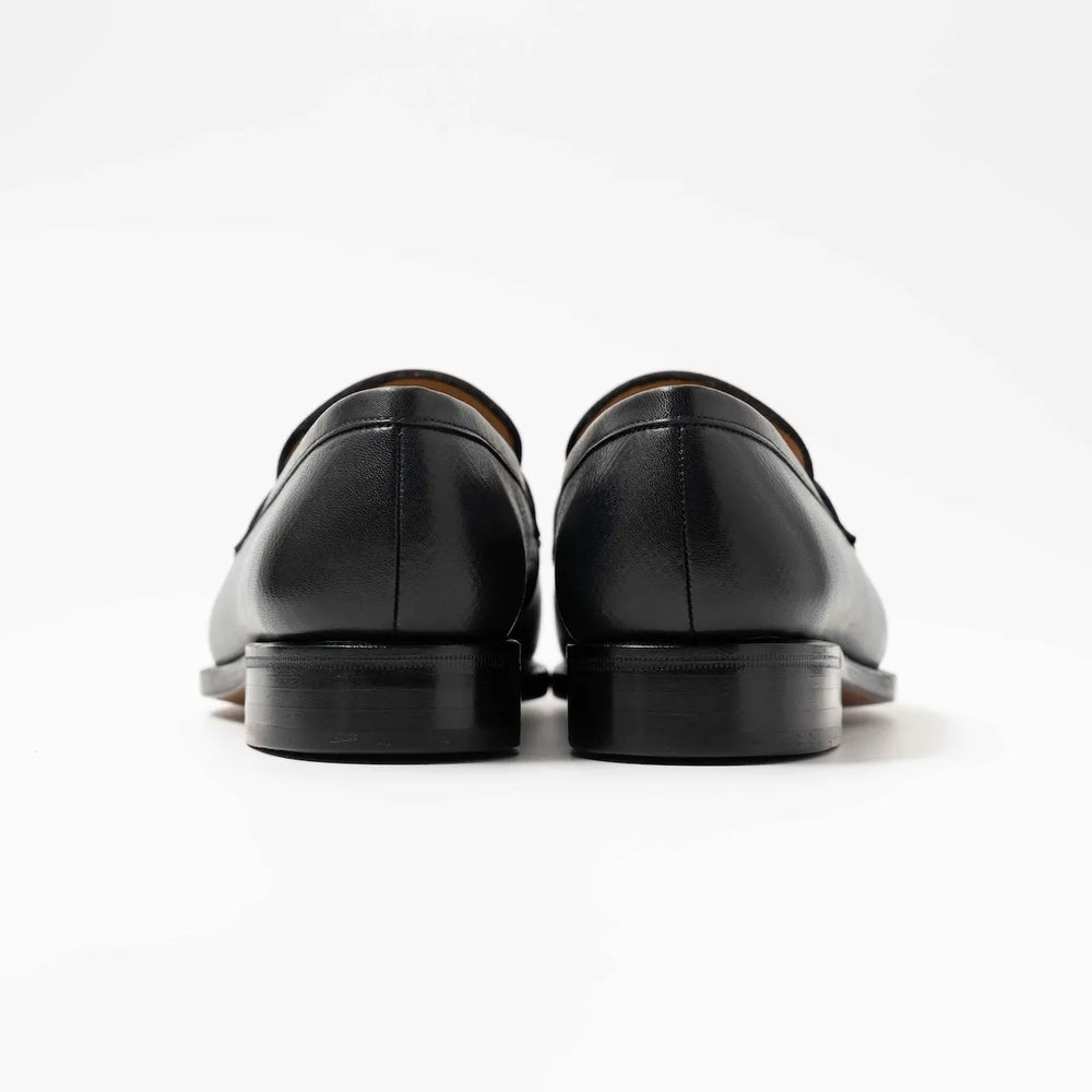 Rear view highlighting the heel shape, stitching, and smooth contours of the black hatch grain loafers.