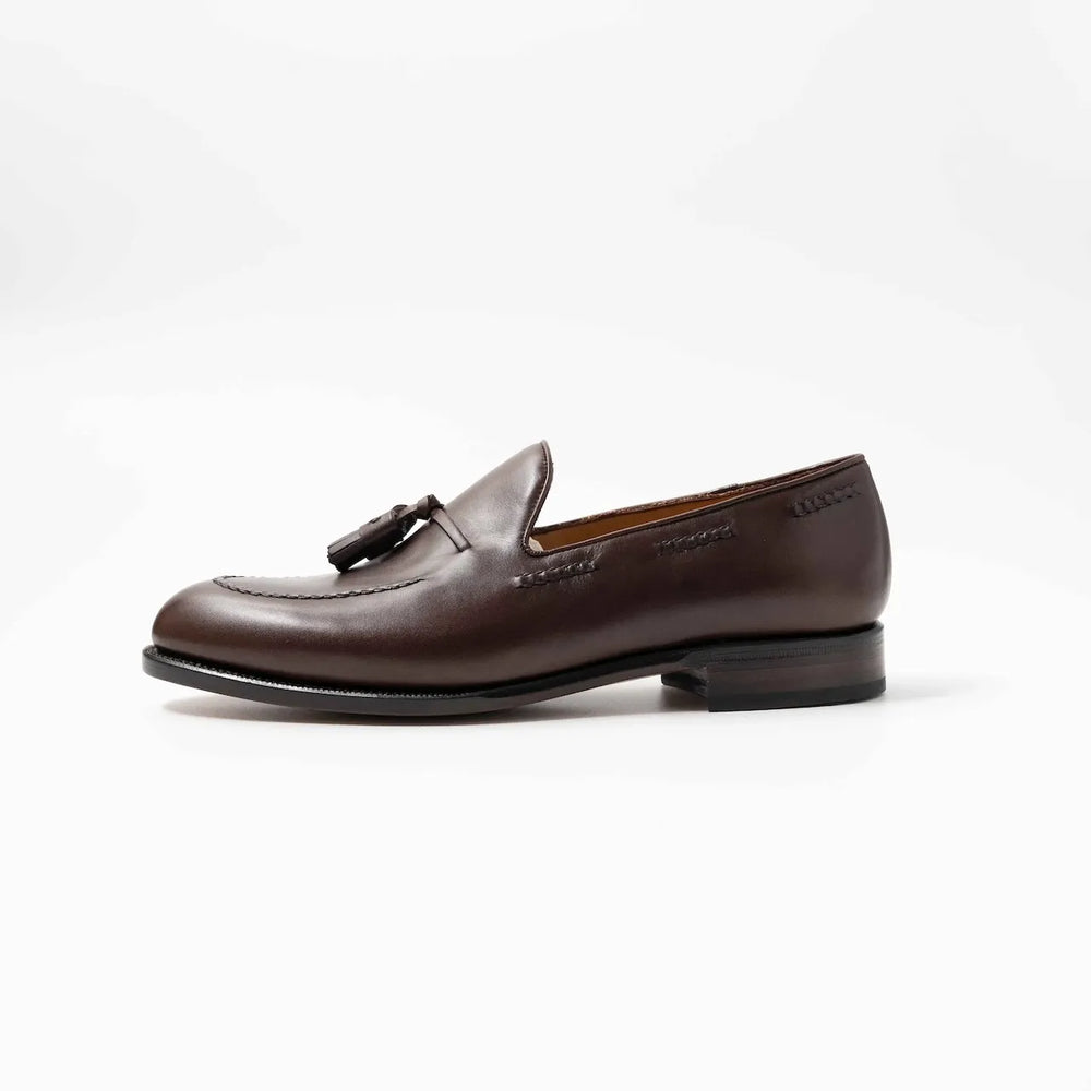 Side profile of the TLB Mallorca Jones Tassel Loafer in dark brown vegano leather with a sleek silhouette and single leather sole.