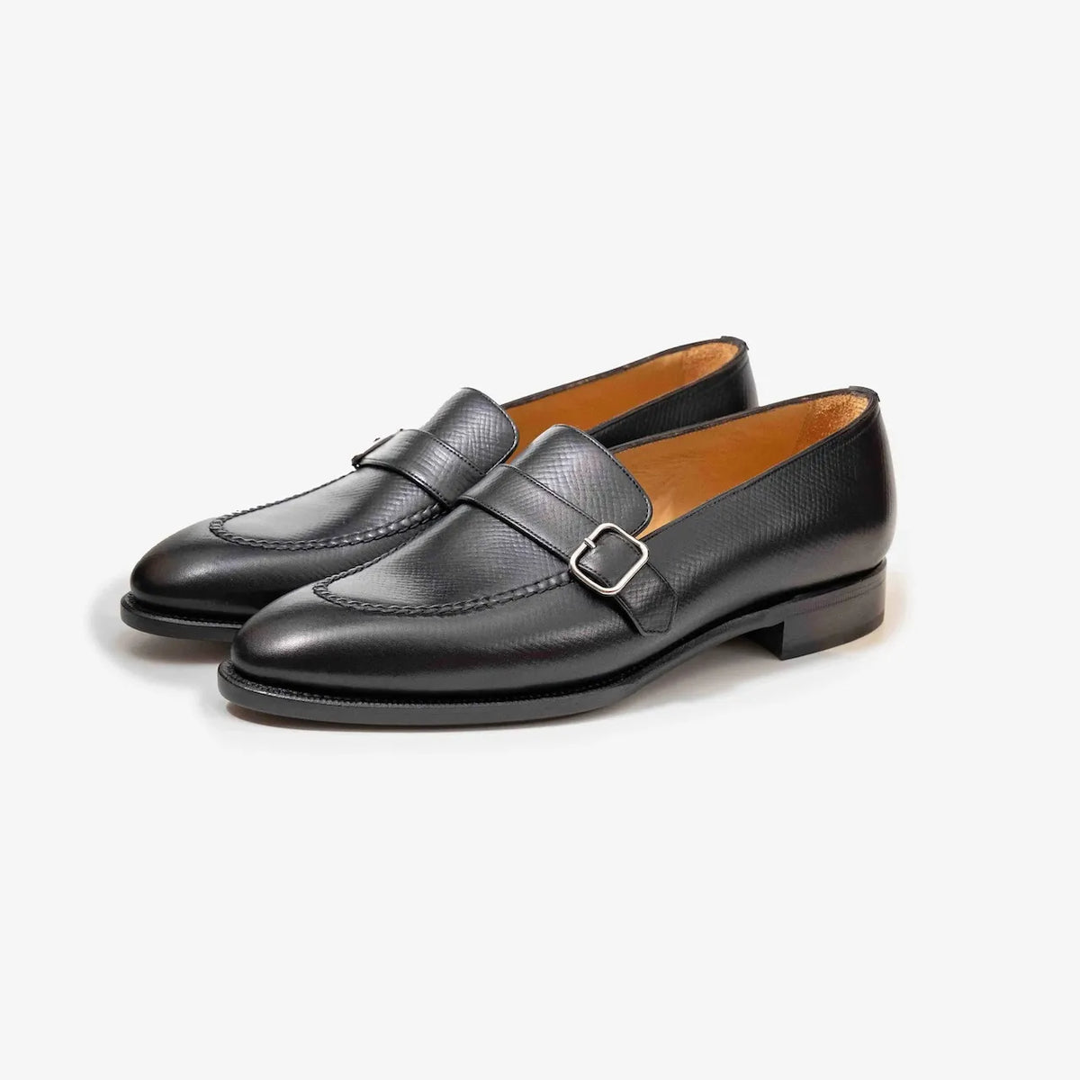 A pair of TLB Mallorca 325 Goya Buckled Loafers in black hatch grain leather, shown at an angle to highlight the elegant buckle and rich texture.