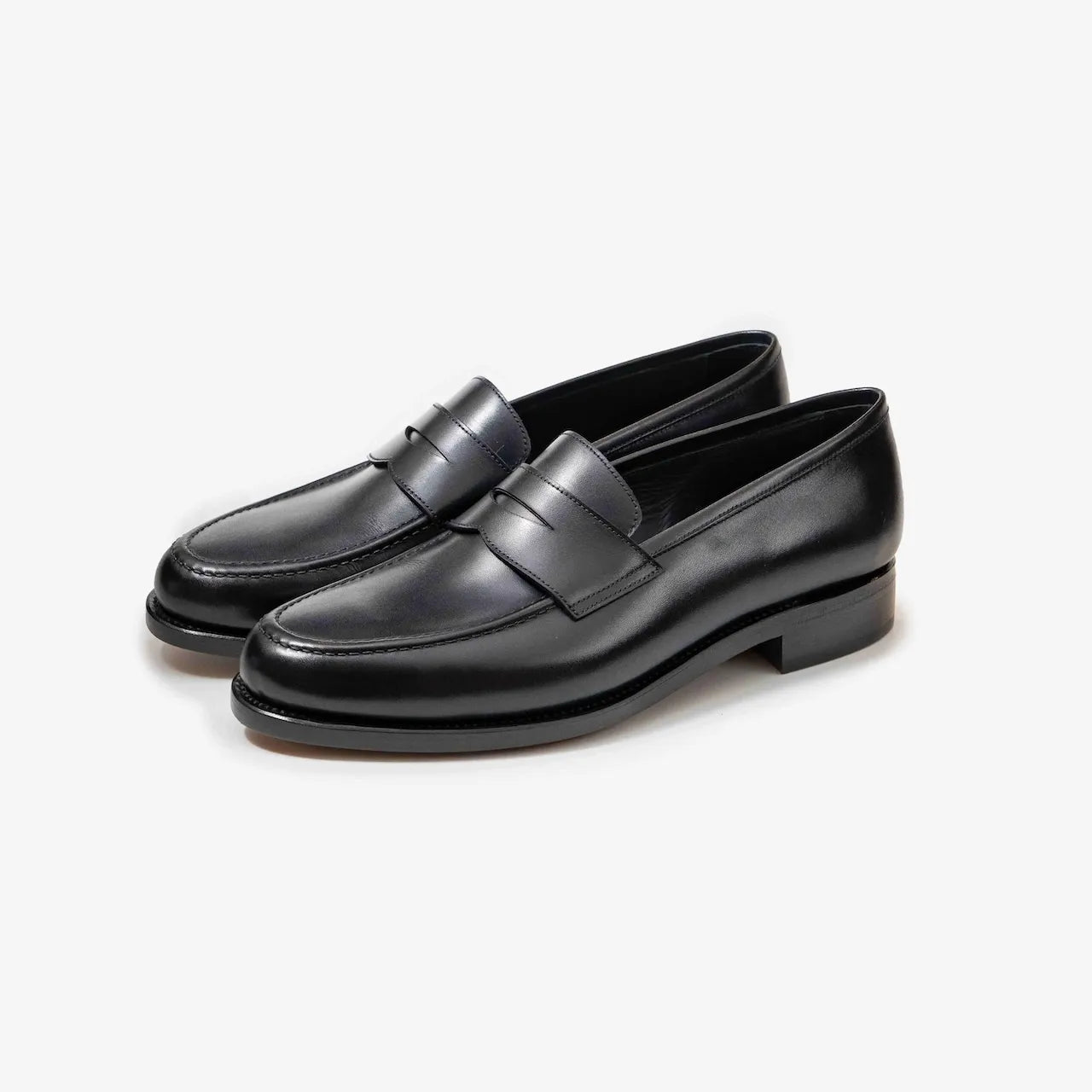 A pair of TLB Mallorca 718 Queens Penny Loafers in black box calf leather, shown at an angle to highlight the elegant silhouette and polished finish.