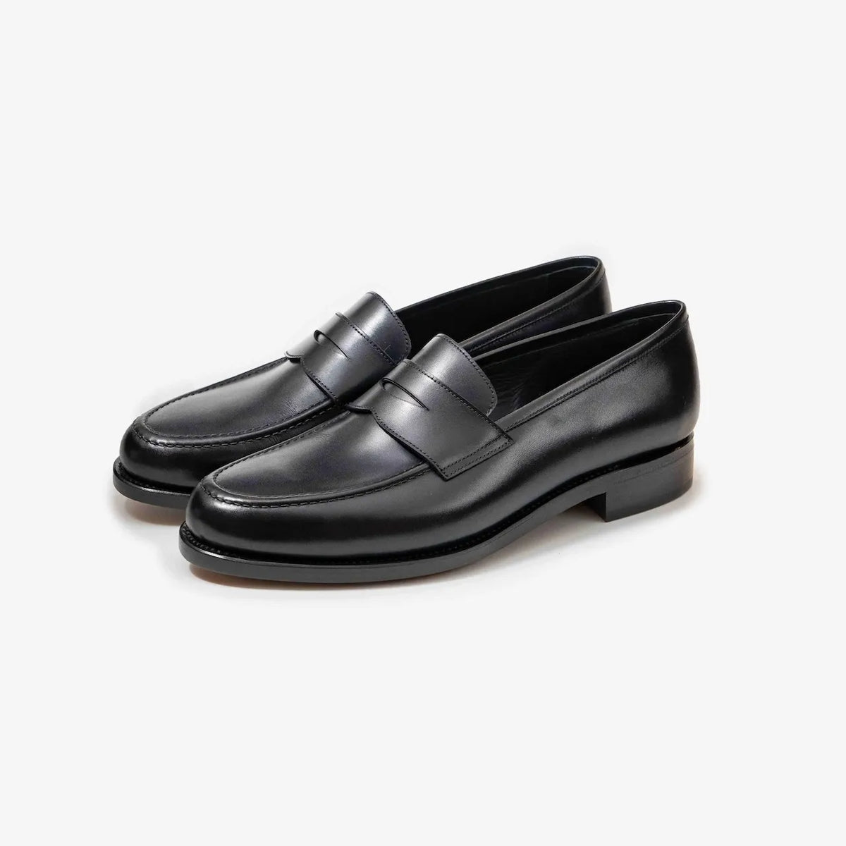 A pair of TLB Mallorca 718 Queens Penny Loafers in black box calf leather, shown at an angle to highlight the elegant silhouette and polished finish.
