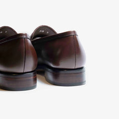 Rear view highlighting the heel curve and craftsmanship of the dark brown vegano penny loafers.