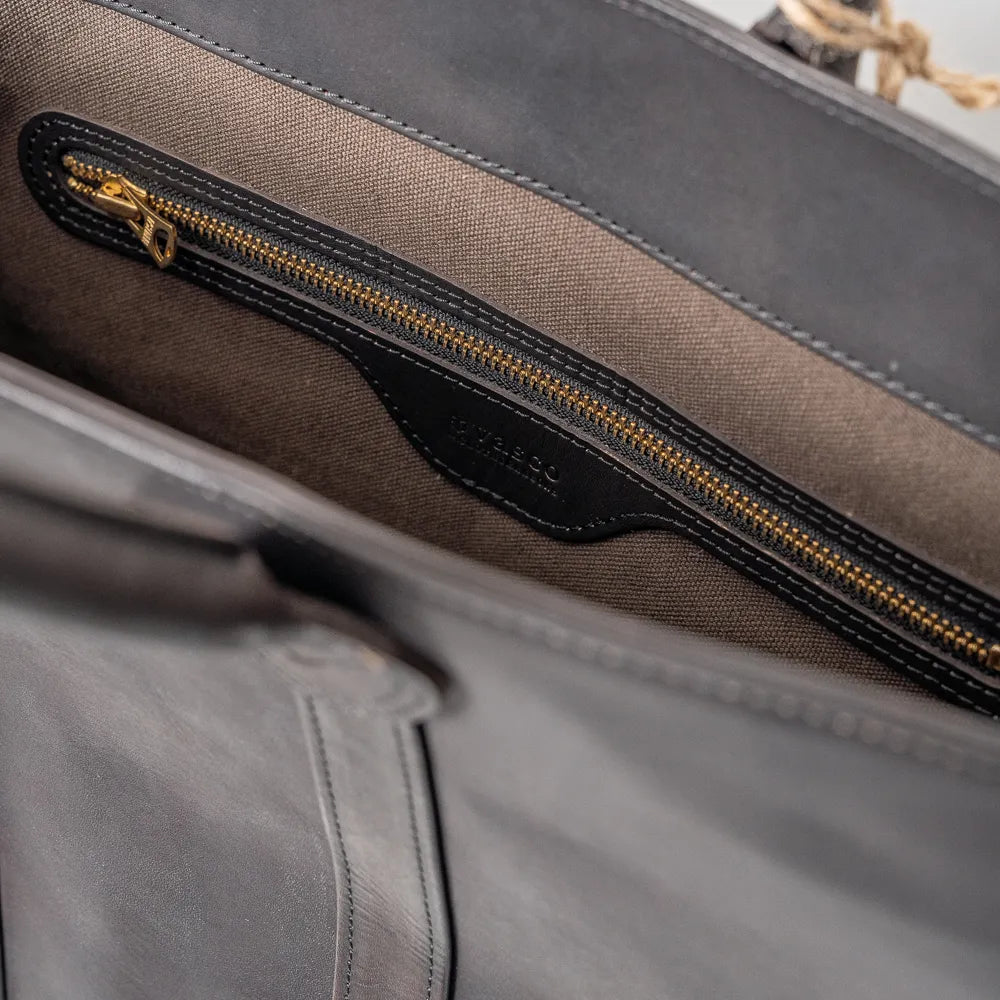 Close-up of the interior zip pocket inside the Vasco x Refinement Leather Tote Black, showing the zipper construction, stitching detail, and leather lining.